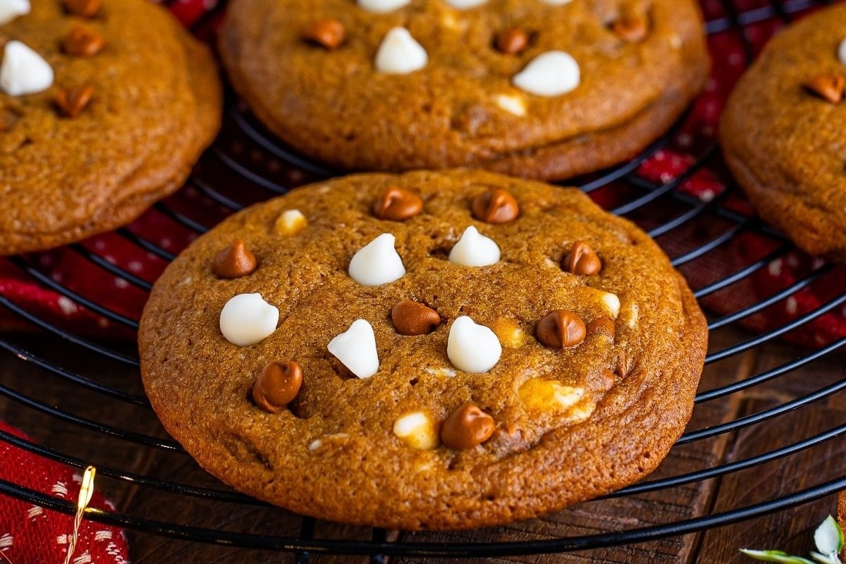 Four cookies with white chocolate chips on a cooling rack, perfect for trying out freezable cookie recipes.
