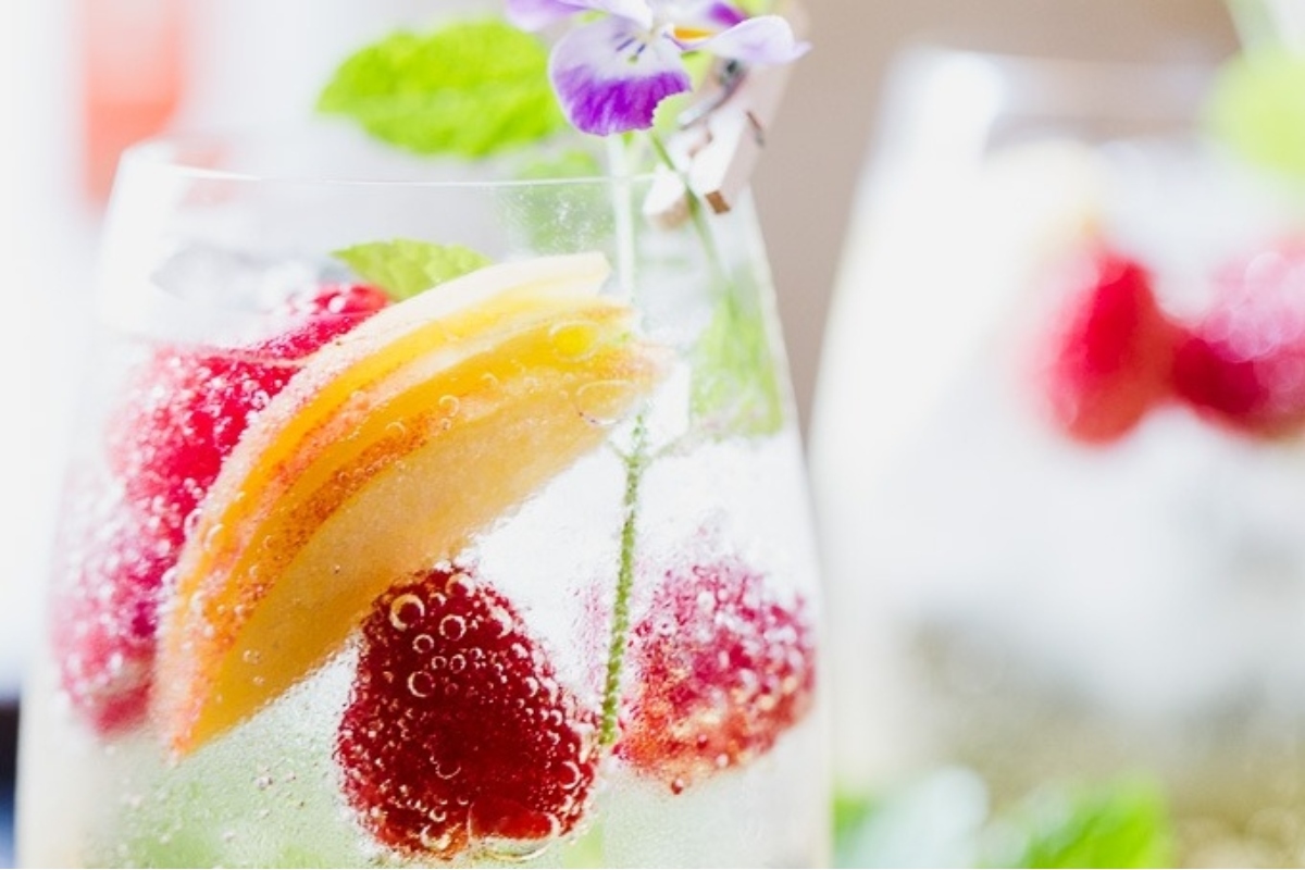 A glass of sparkling wine with raspberries and mint, perfect for Christmas cocktails.