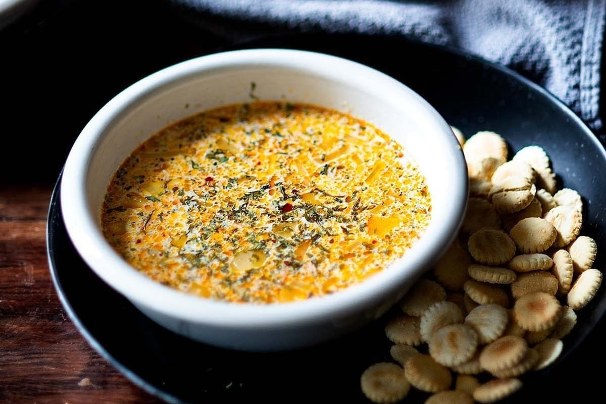 A bowl of cheesy dip with crackers on a table at a New Year's dinner celebration.