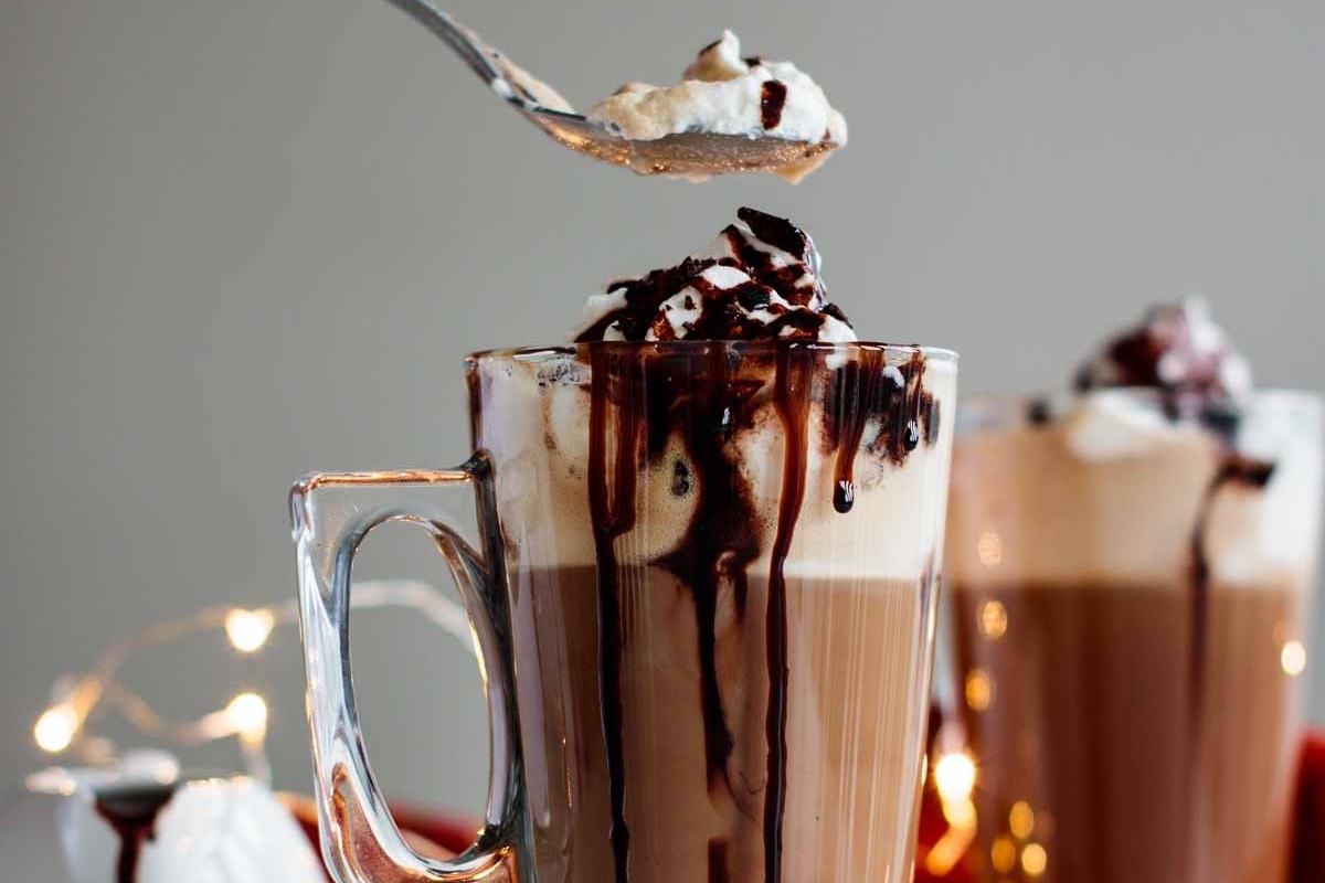 A cup of hot chocolate with whipped cream and chocolate sauce from Starbucks, perfect for the holiday season.