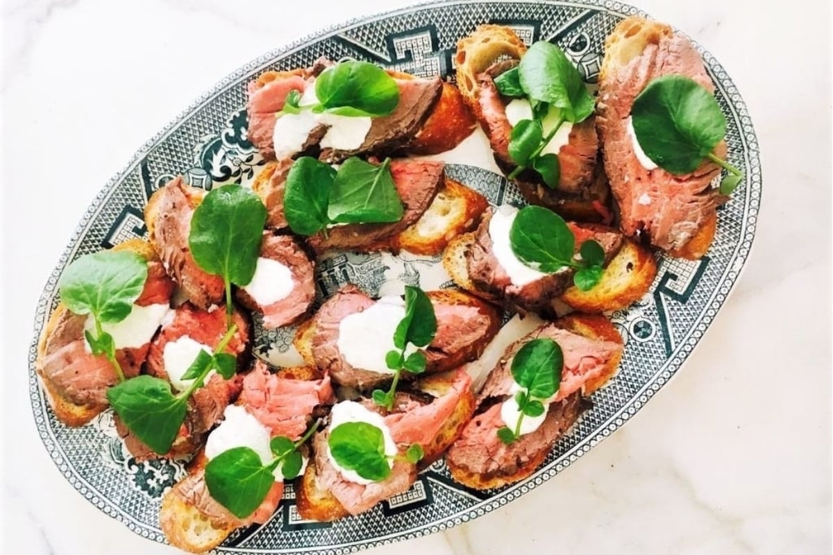 A lavish plate showcasing a delectable fusion of succulent meat and vibrant greens, impeccably presented on a luxurious marble table.