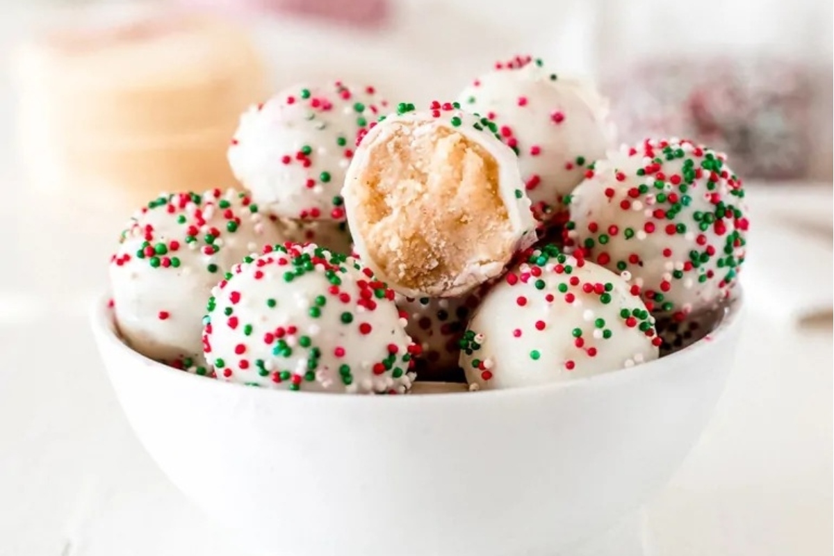 No bake peanut butter balls in a white bowl with sprinkles, perfect for Christmas desserts.