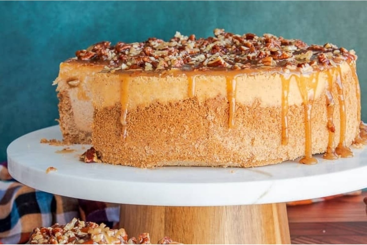 Holiday pumpkin cheesecake with pecans on a white plate.