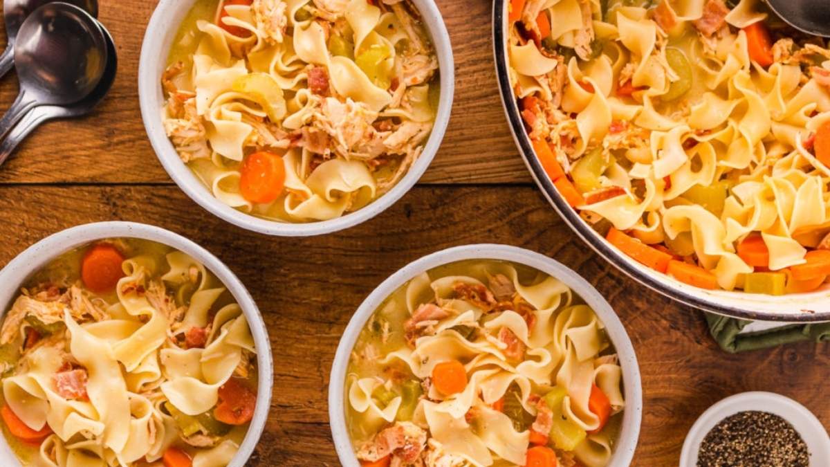 Chicken noodle soup in bowls on a wooden table.