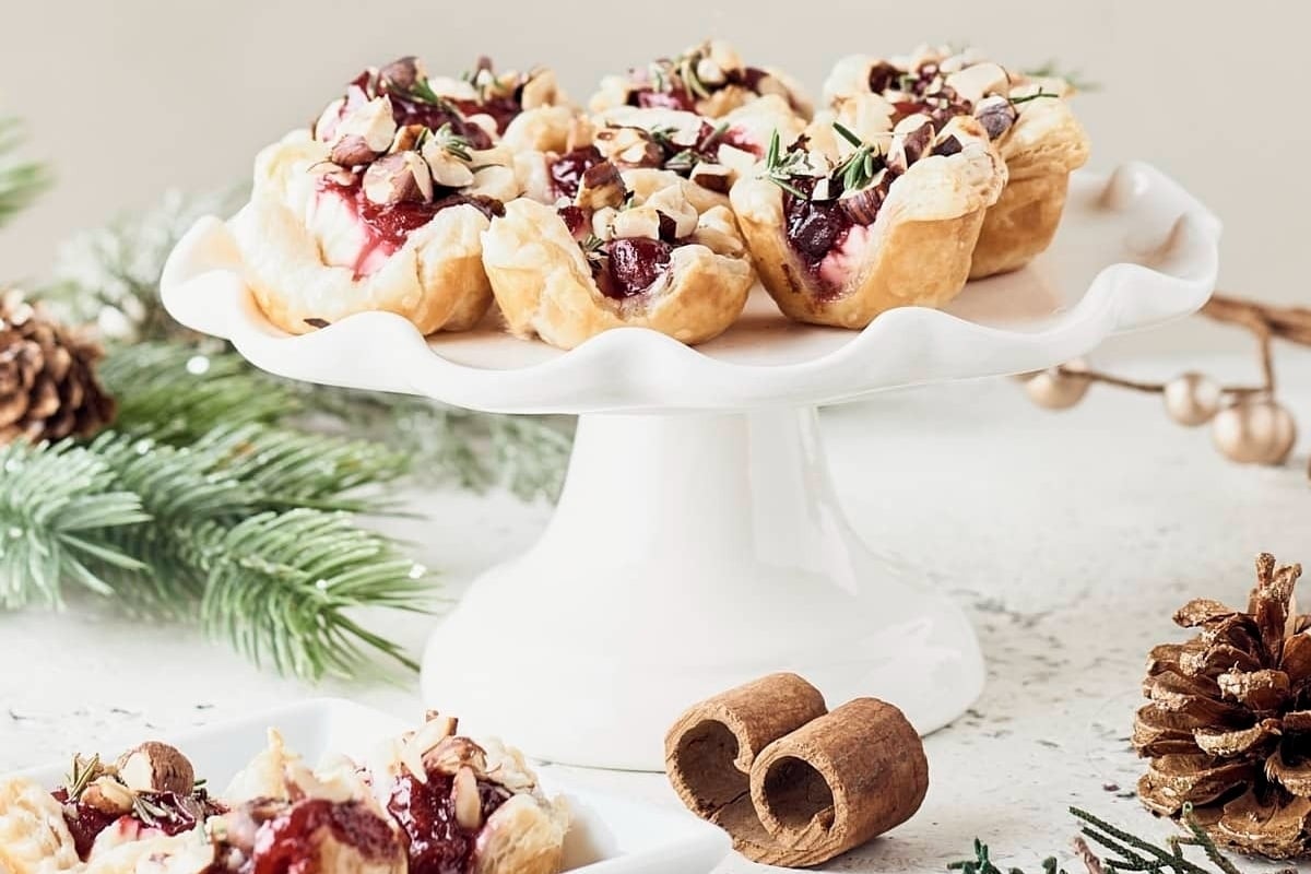 New Year's Eve cranberry tarts on a white plate with pine cones.