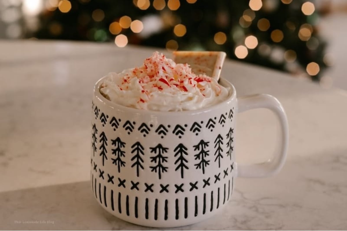 A mug of hot chocolate with whipped cream and sprinkles, perfect for indulging in a warm and comforting treat.