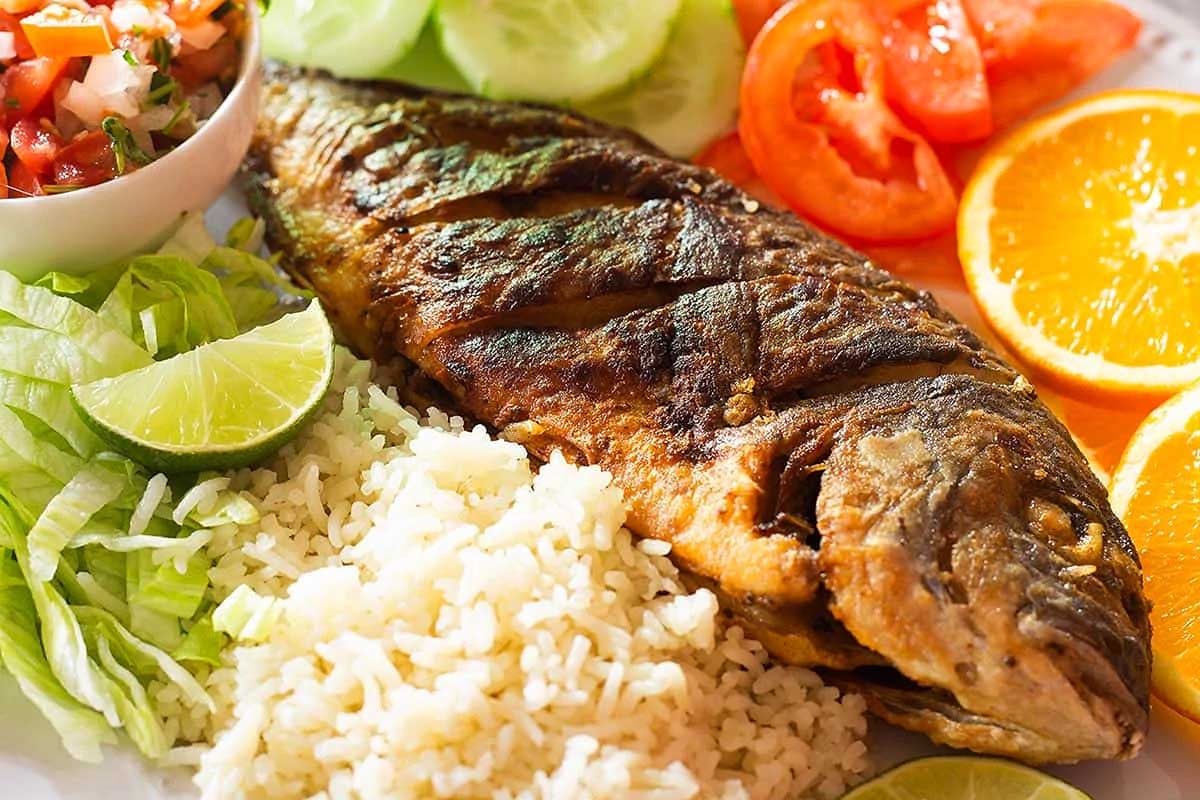 A plate featuring a delicious feast of seven fishes, consisting of fish, rice, and vegetables.