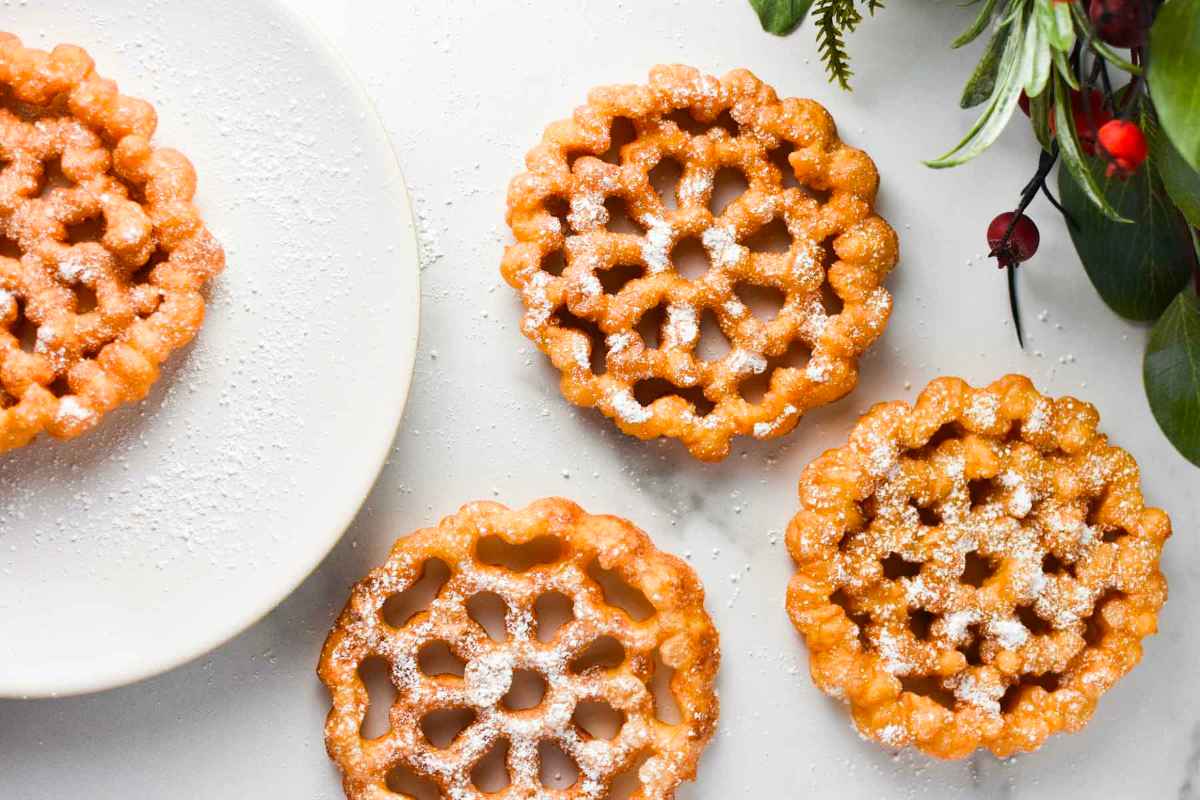 Four waffle cookies on a white plate with greenery.
