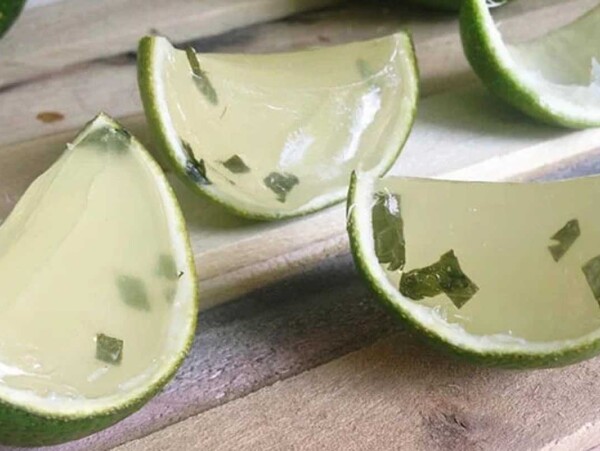 A slice of lime sitting on top of a cutting board, perfect for enhancing jello shots.