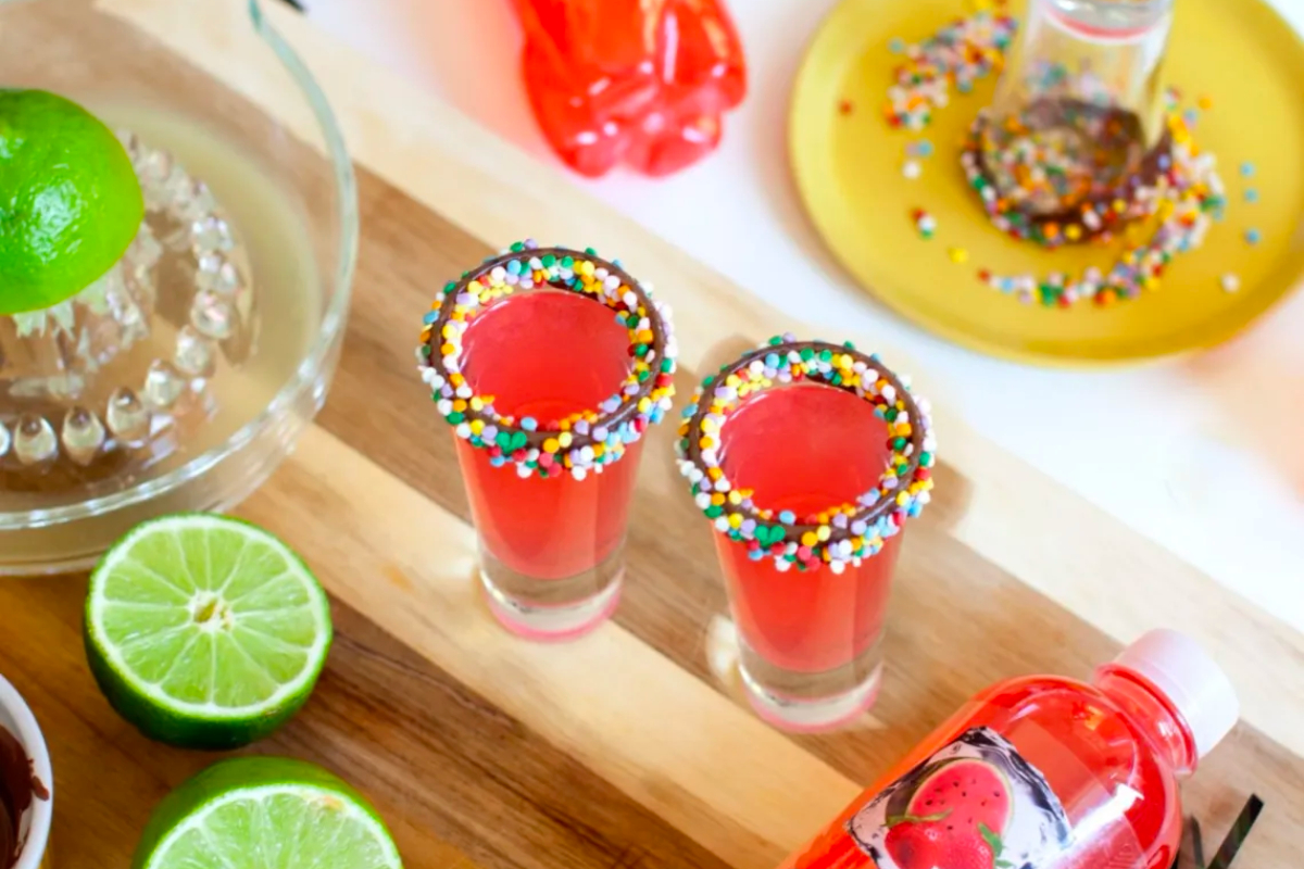 Margaritas with sprinkles and limes on a cutting board at a New Year's eve party.