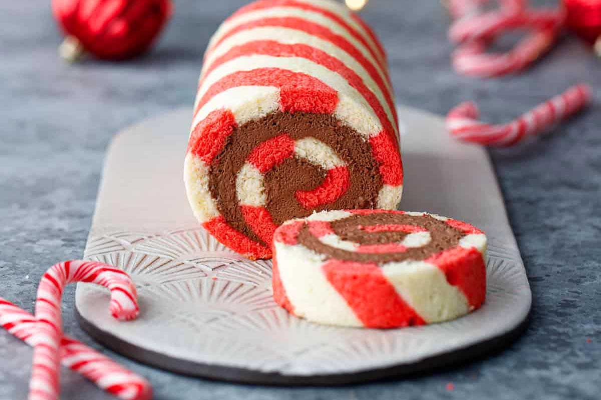 A hot chocolate coco candy roll is sitting on a plate with candy canes.