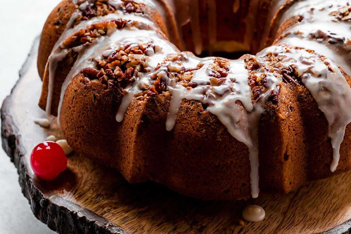 A chocolate bundt cake with icing and cherries on top.