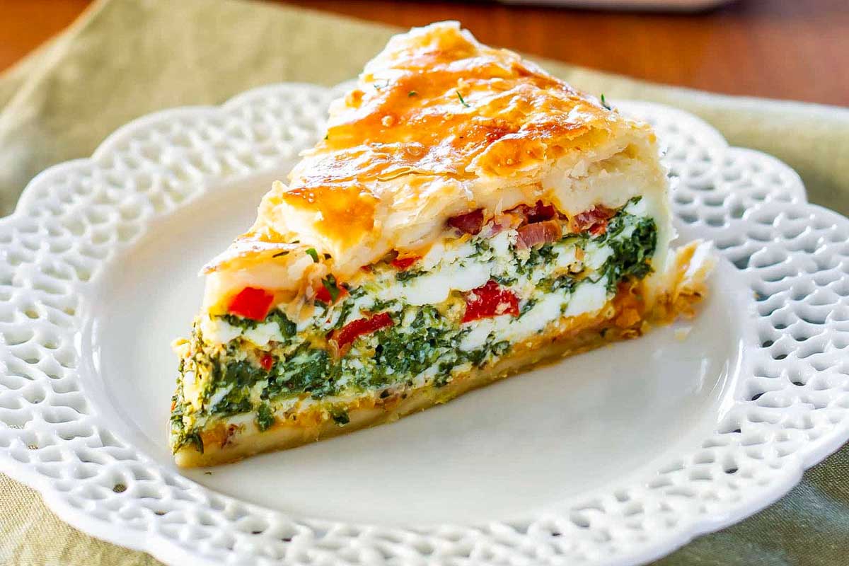 A delicious slice of cheese and spinach pie, perfect for a New Year's Day Brunch, elegantly presented on a plate.