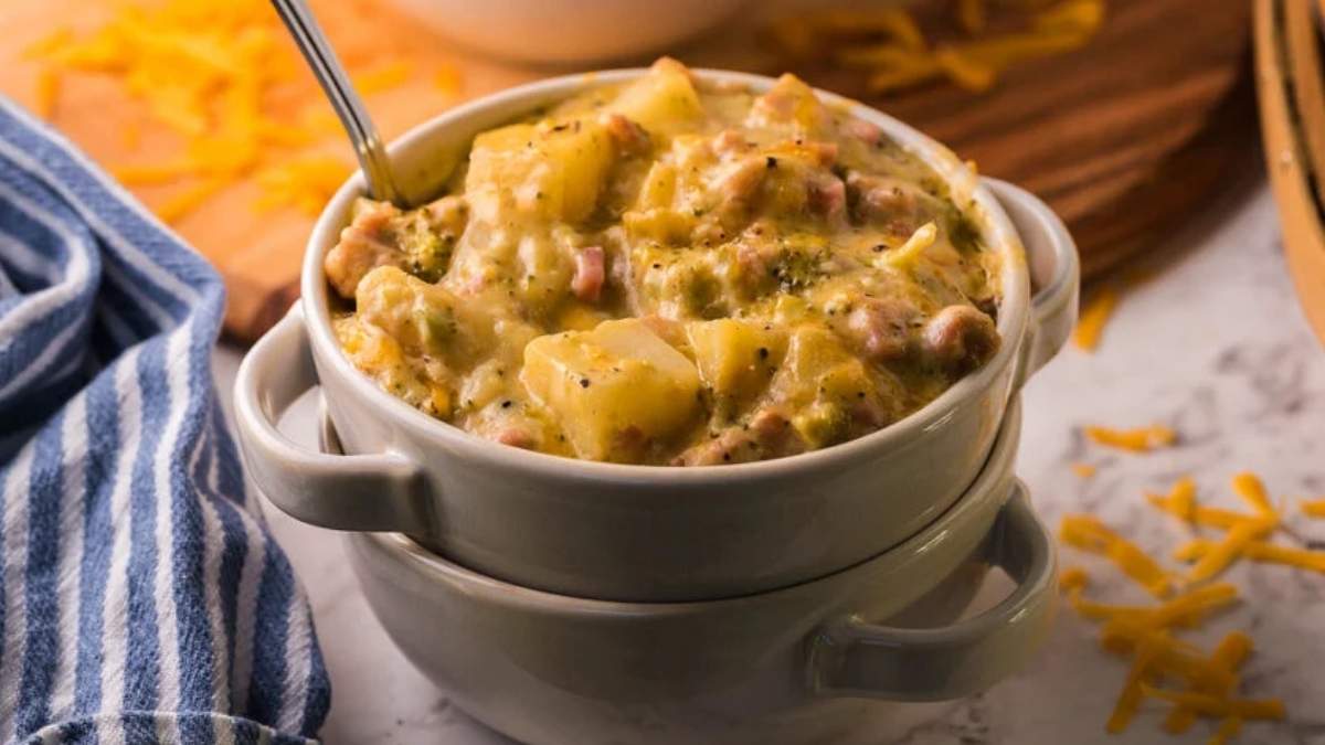 Cheesy potato casserole in a white bowl with a spoon.