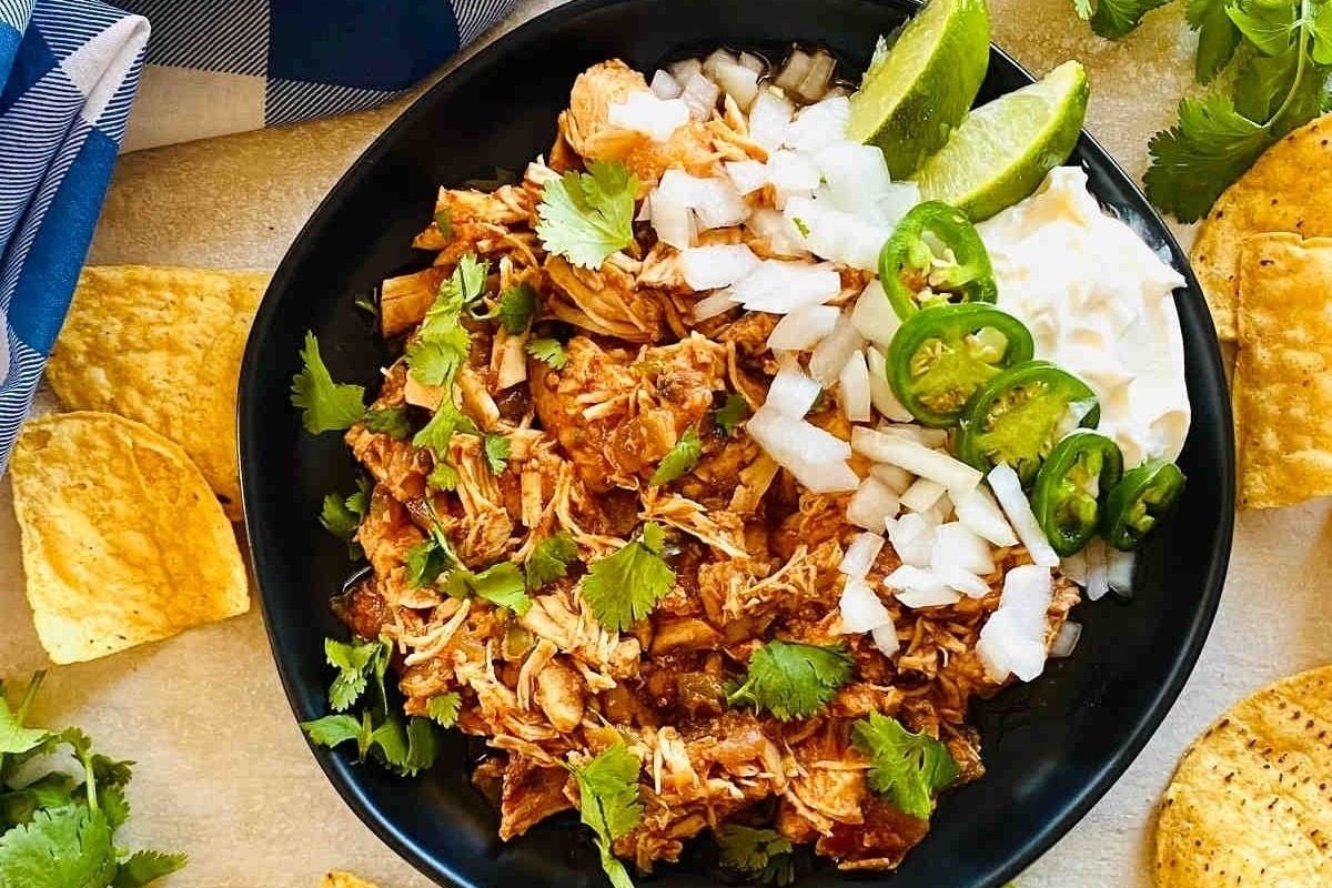 Instant Pot Mexican pulled pork served in a black bowl with tortilla chips, perfect for a cozy winter meal.