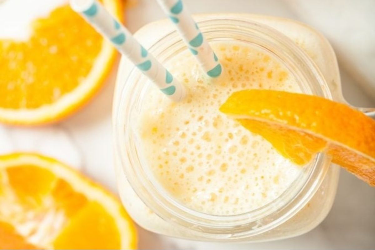 A jar of orange juice with a pinwheel and a straw in it.