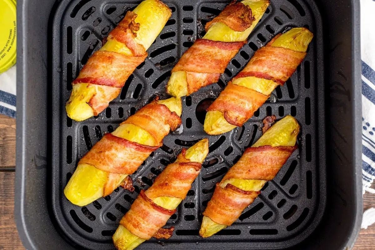 Bacon wrapped squash on a baking sheet.