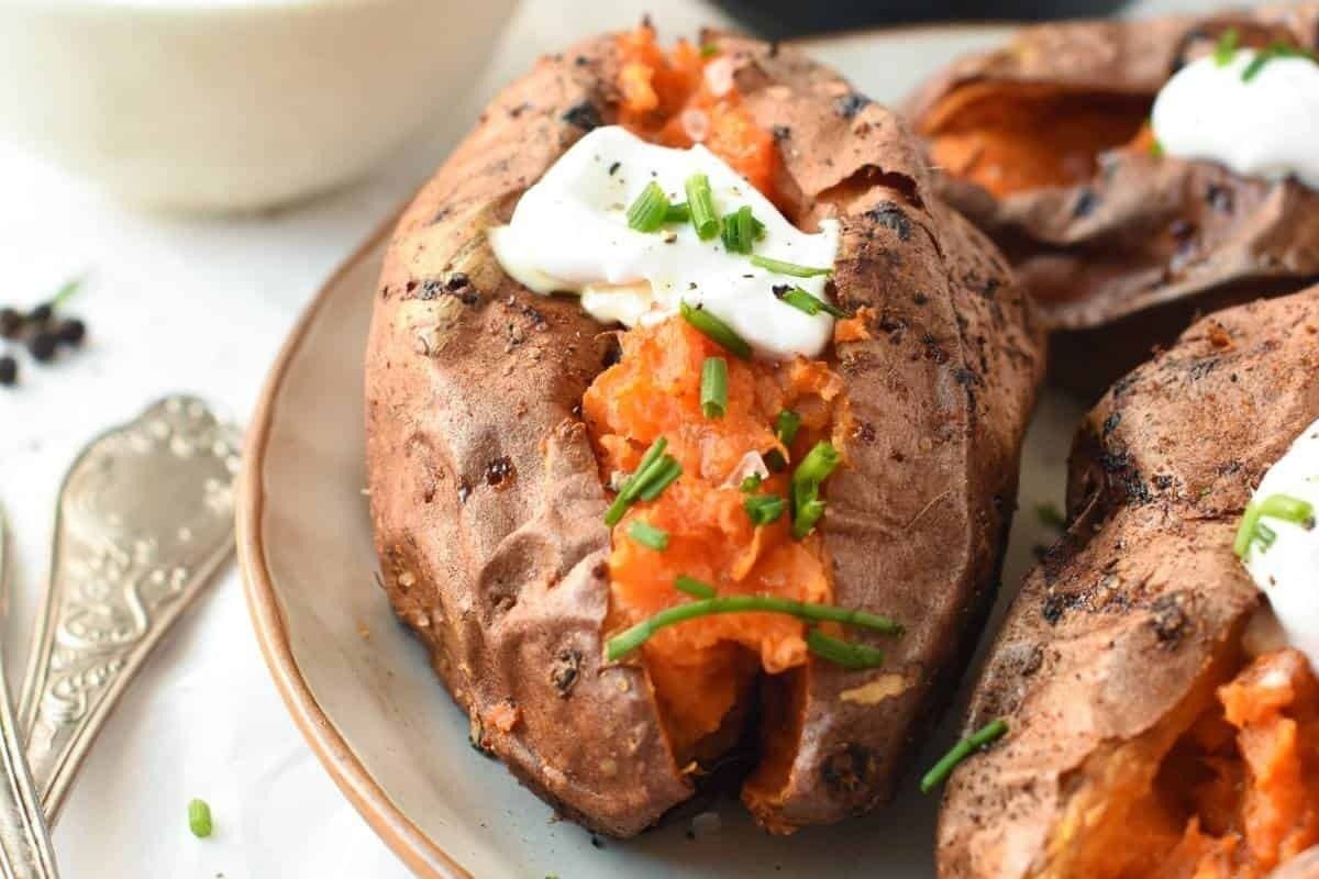 Wholesome grilled sweet potatoes with sour cream and chives on a plate.