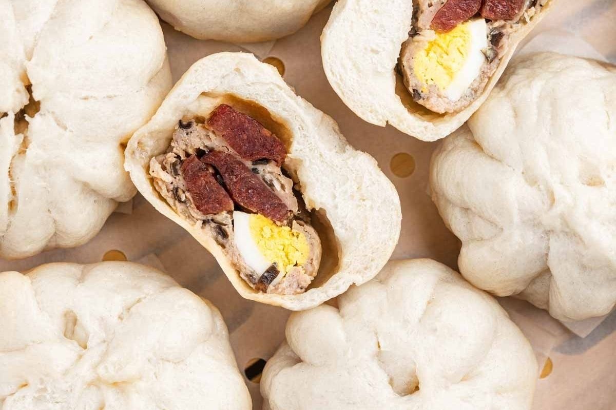 Steamed buns with fillings of egg, sausage, and meat—some cut open to reveal the inside—make delicious additions to your collection of Lunar New Year recipes.