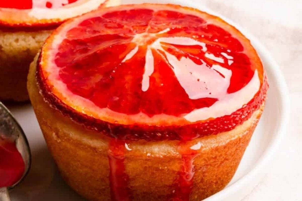 Two citrus cupcakes made with blood orange on a plate with a spoon.