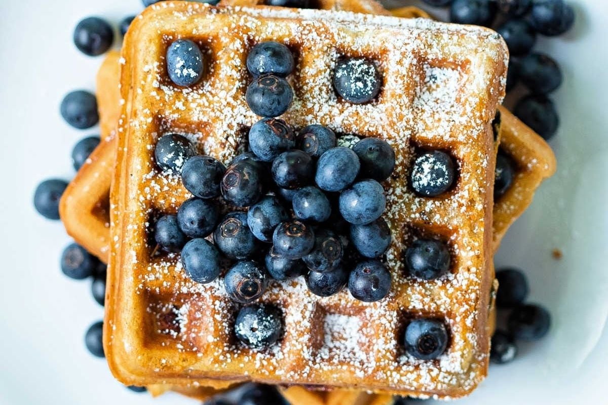 Delicious waffles topped with fresh blueberries and a dusting of powdered sugar.