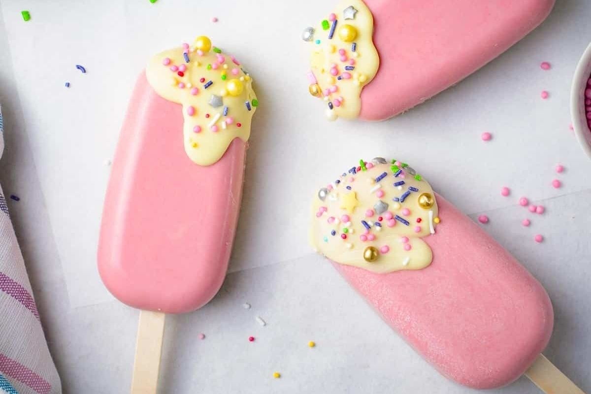 Three pink popsicles with sprinkles on them, perfect for a refreshing treat in hot weather or as a fun dessert for any occasion.