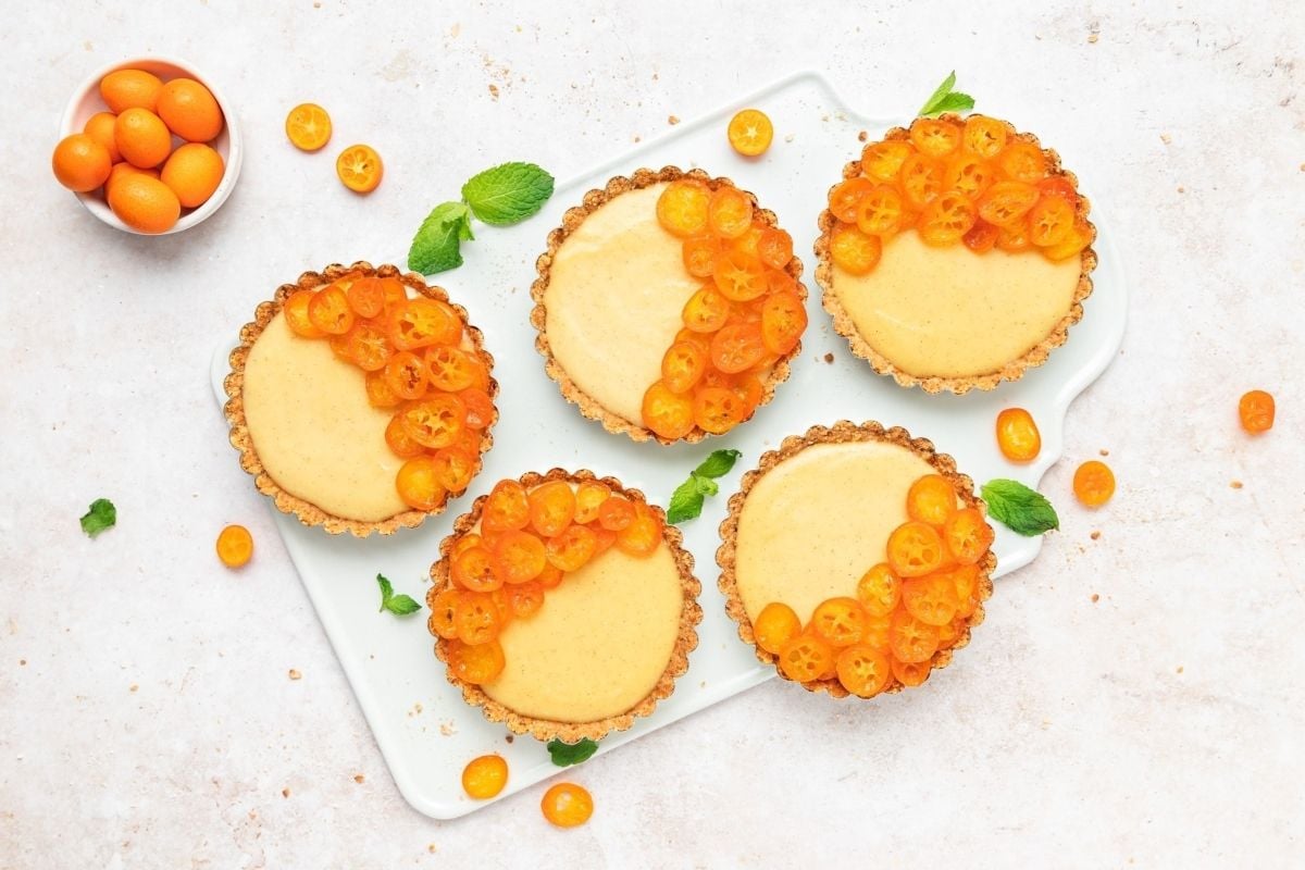 Four apricot tarts on a white plate for citrus recipes.