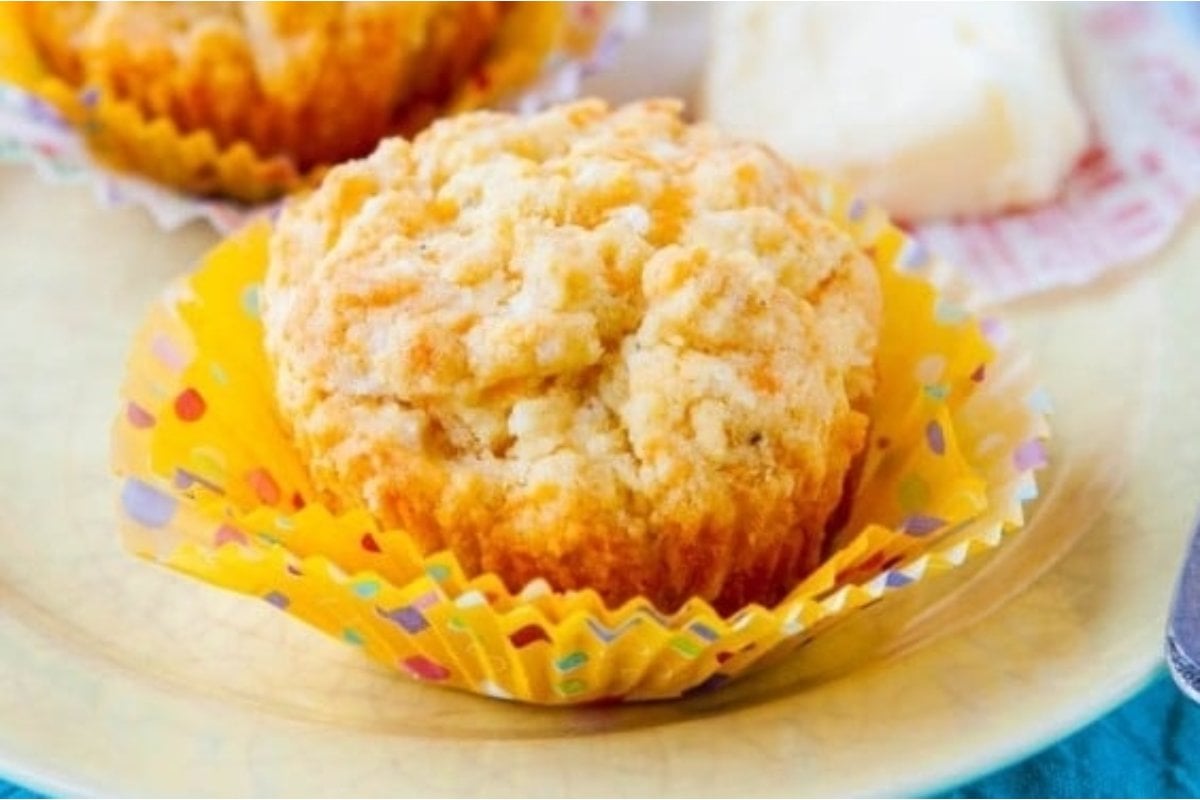 A close-up image of a freshly baked savory muffin in a colorful cupcake liner on a ceramic plate.