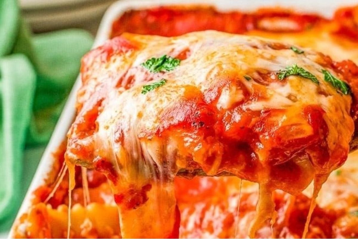 A plate of lasagna topped with cheese and sauce.