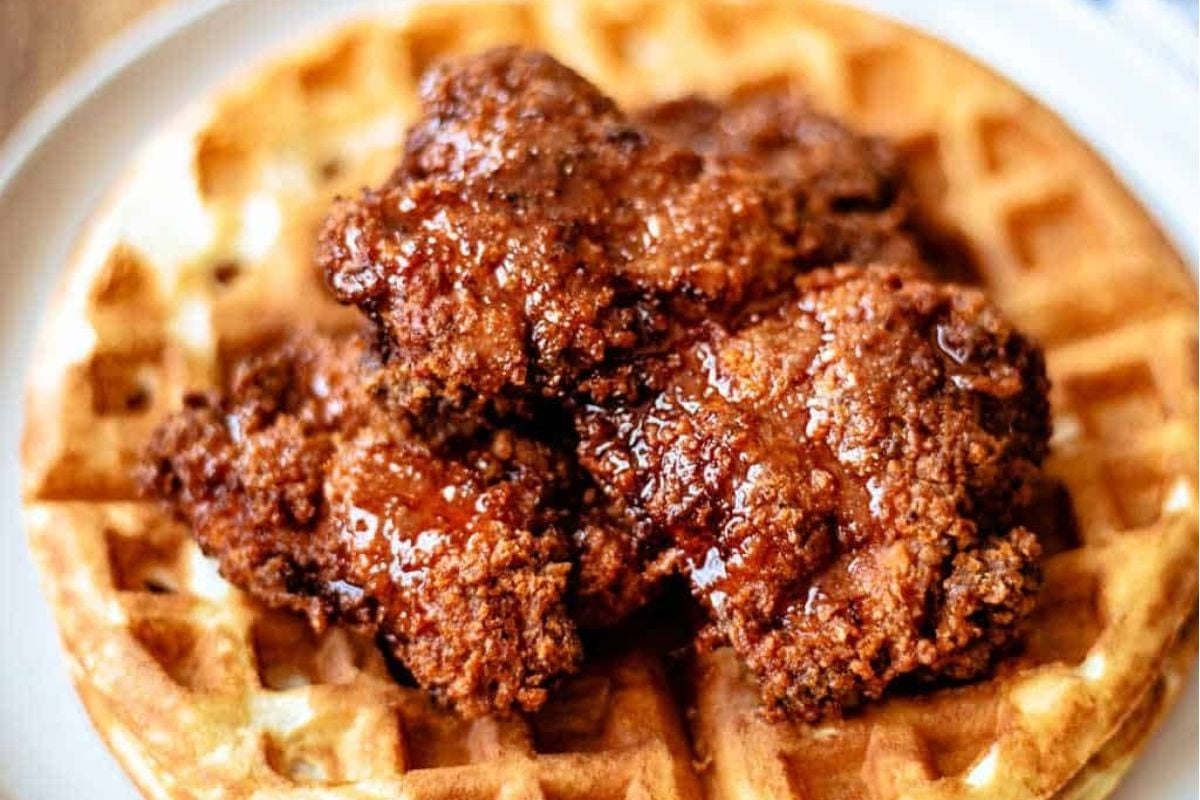 Delicious fried chicken served with a crispy waffle on a plate.