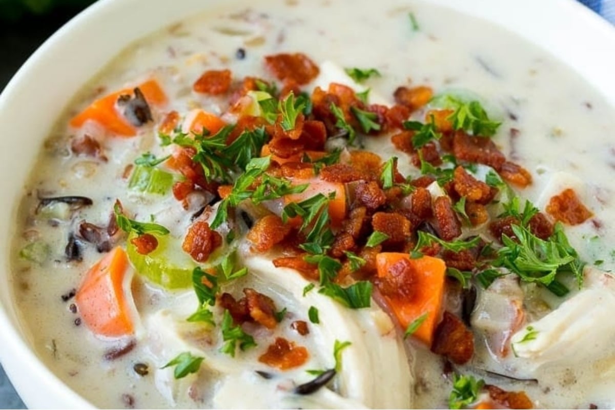 A creamy bowl of chicken and wild rice soup with bacon and parsley.
