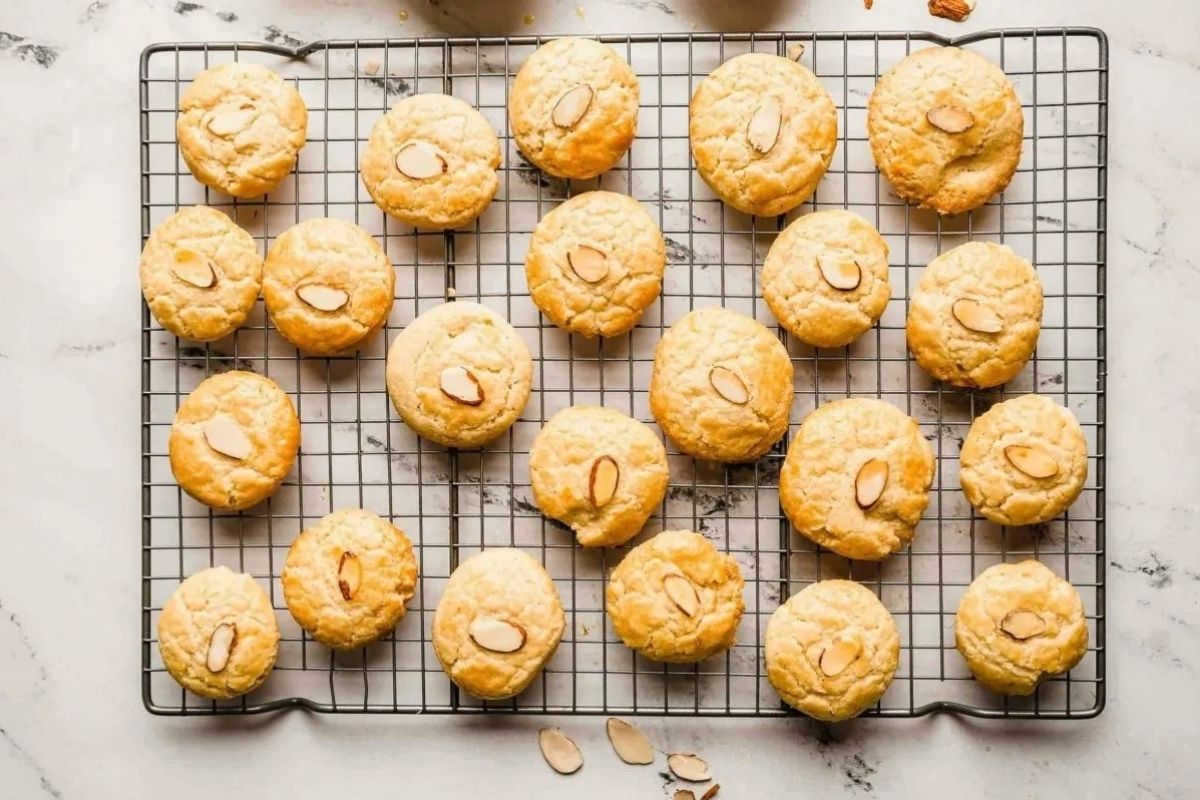 Twenty almond cookies with sliced almonds on top cooling on a wire rack over a marble surface—a delightful addition to your collection of Lunar New Year recipes.