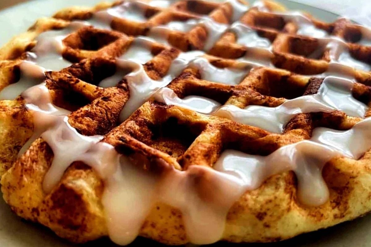 A delectable waffle drizzled with cinnamon icing on a plate.
