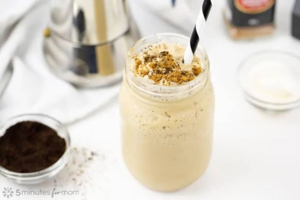 An iced coffee in a mason jar garnished with pinwheel recipes on granola.
