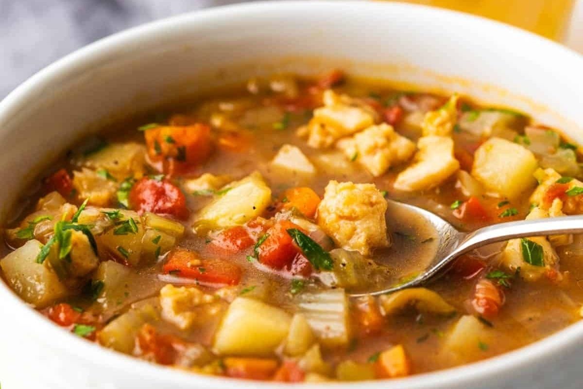 A hearty bowl of homemade chicken and vegetable soup, served with a spoon.