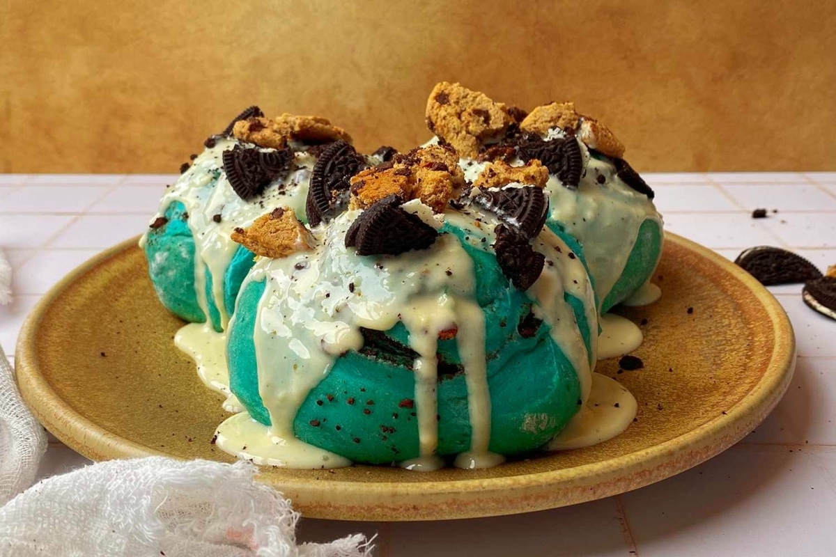A plate with a blue ice cream and Oreo cookies on it.