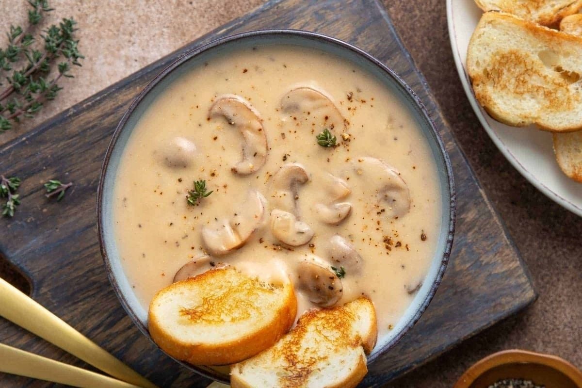 Creamy mushroom soup served with bread and croutons.
