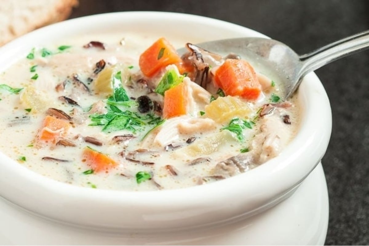 A delicious bowl of chicken and wild rice soup with warm bread.