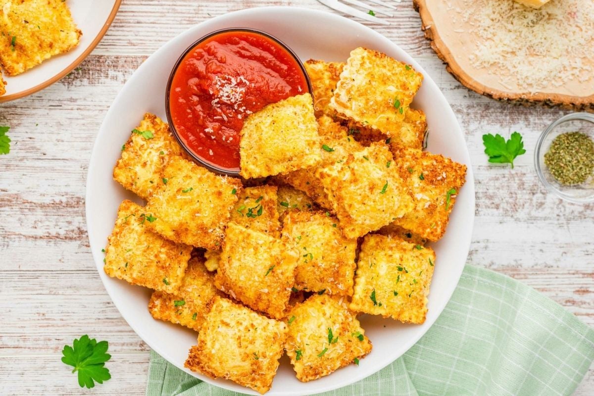Cheesy croutons in a white bowl on a wooden table perfect for ravioli recipes.