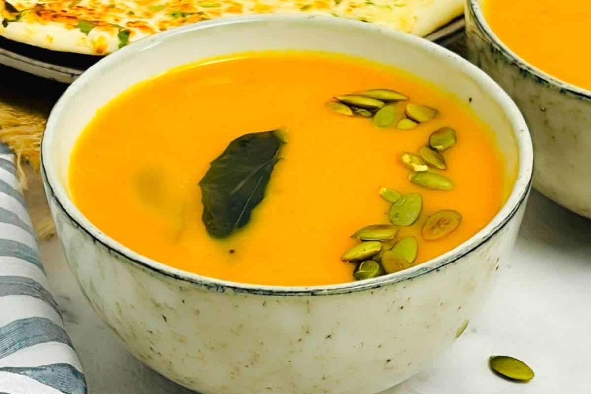Two bowls of creamy pumpkin soup with pumpkin seeds.