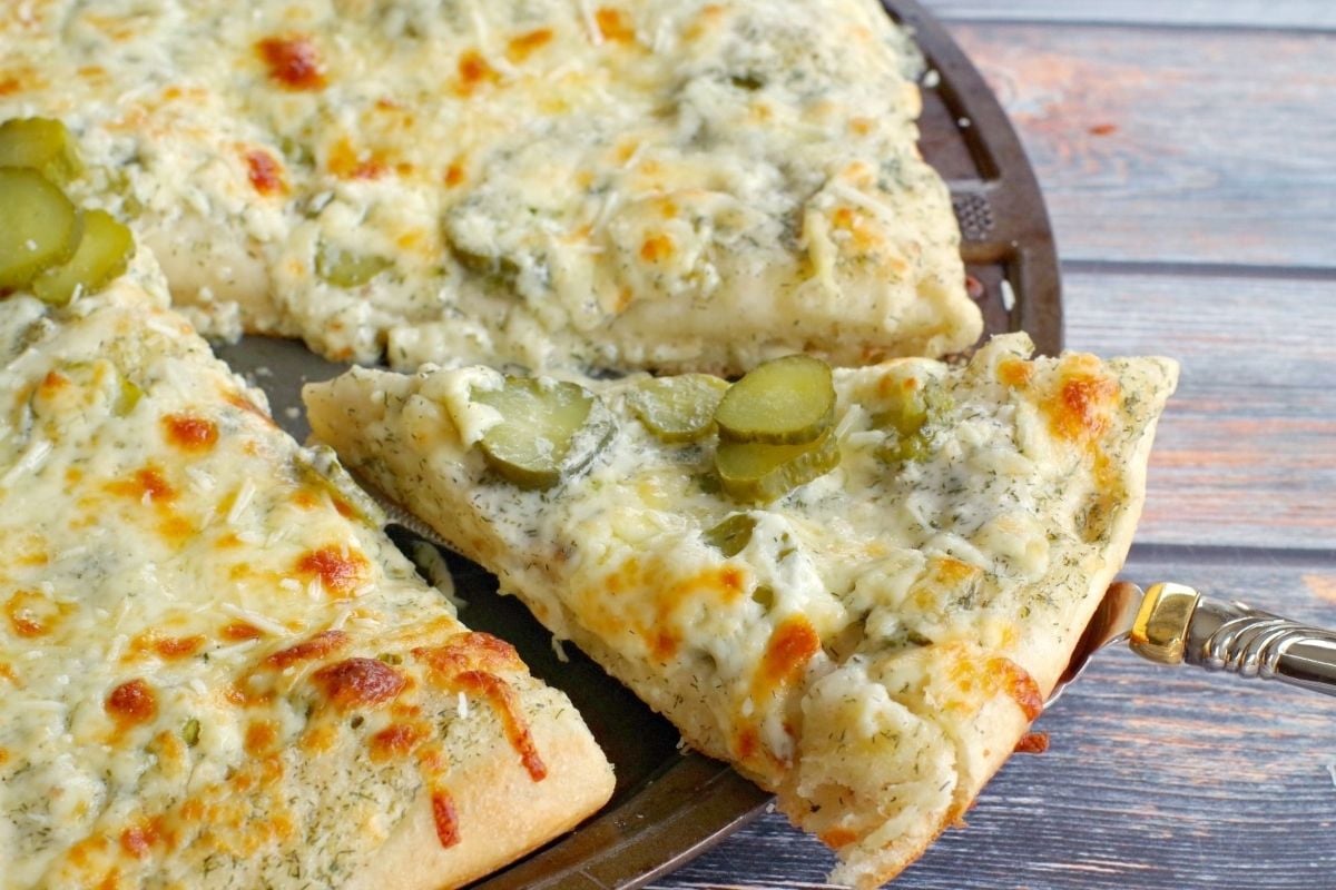 A slice of pizza with cheese and pickles, perfect for pickle lovers.