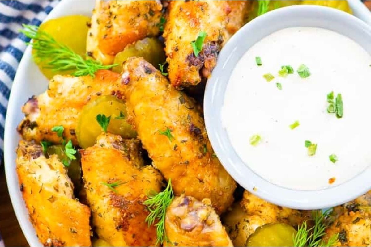 Chicken wings with dipping sauce in a white bowl.