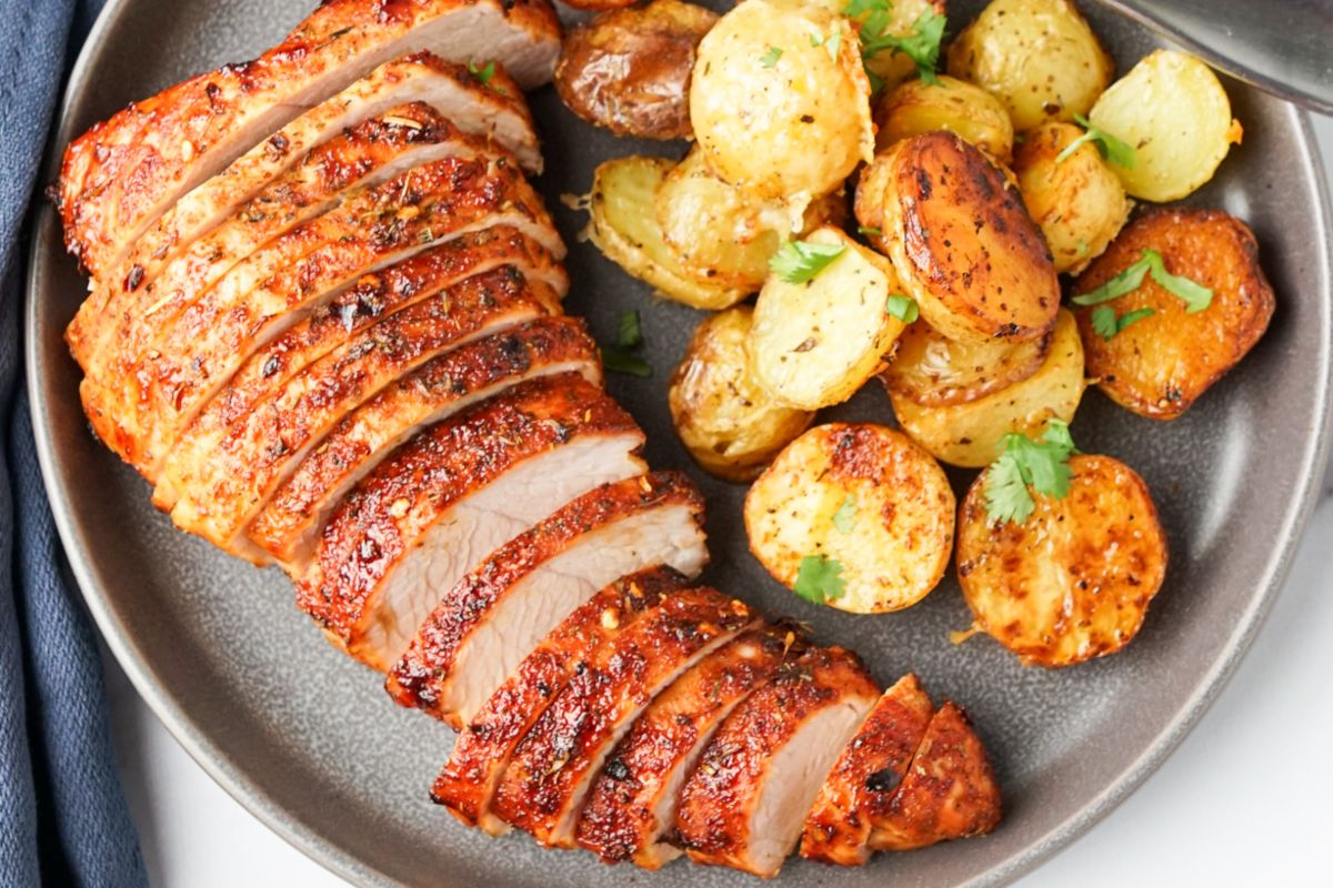 Wholesome sliced pork tenderloin with potatoes on a plate.