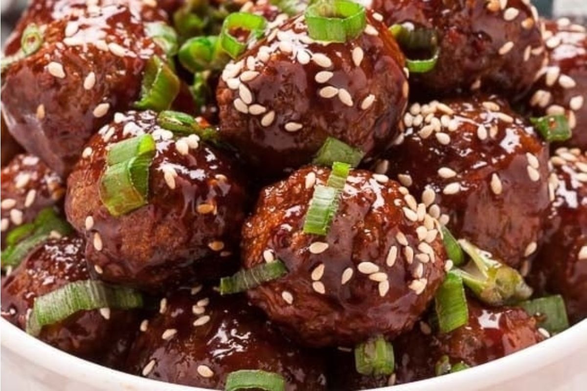 Meatballs coated in a glossy sauce, topped with sesame seeds and sliced green onions, make a festive addition to your Lunar New Year recipes. Served in a white bowl for a beautiful presentation.