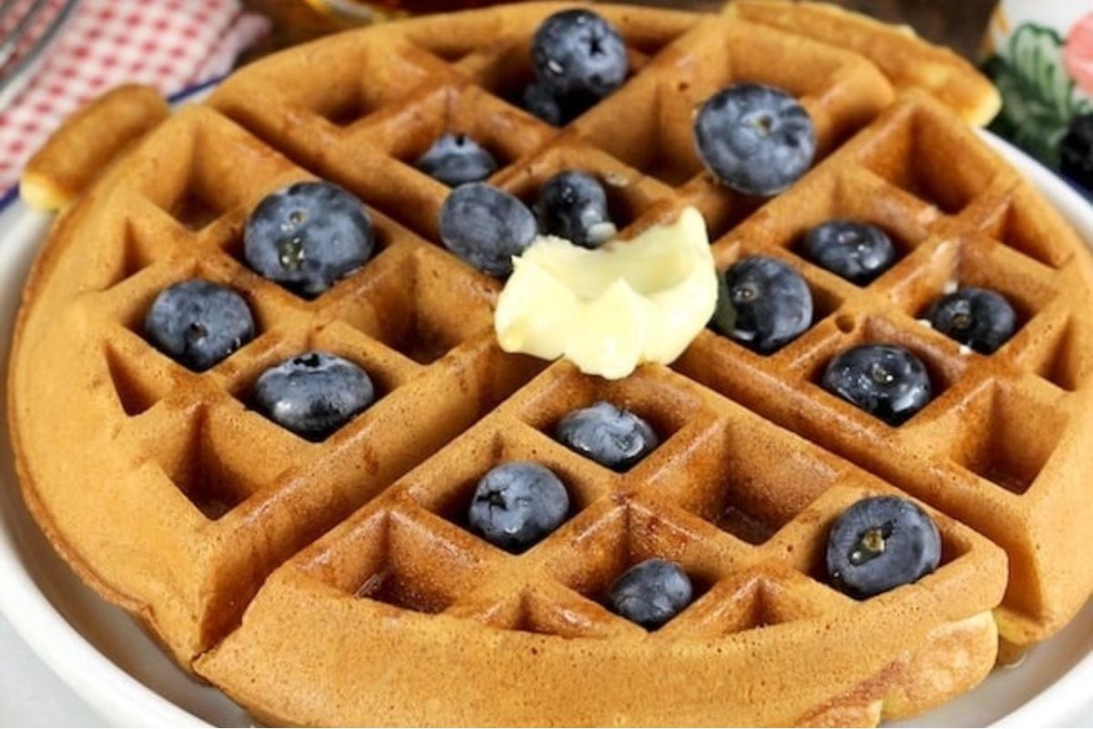 Waffles with blueberries and butter on a plate, prepared using a delightful waffle recipe.