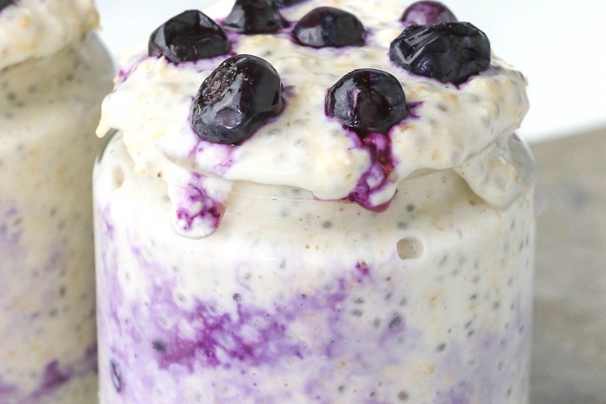 Jar of overnight oats topped with blueberries, with some oats and juice spilling over the rim—perfect for fun Valentine's breakfasts for kids.