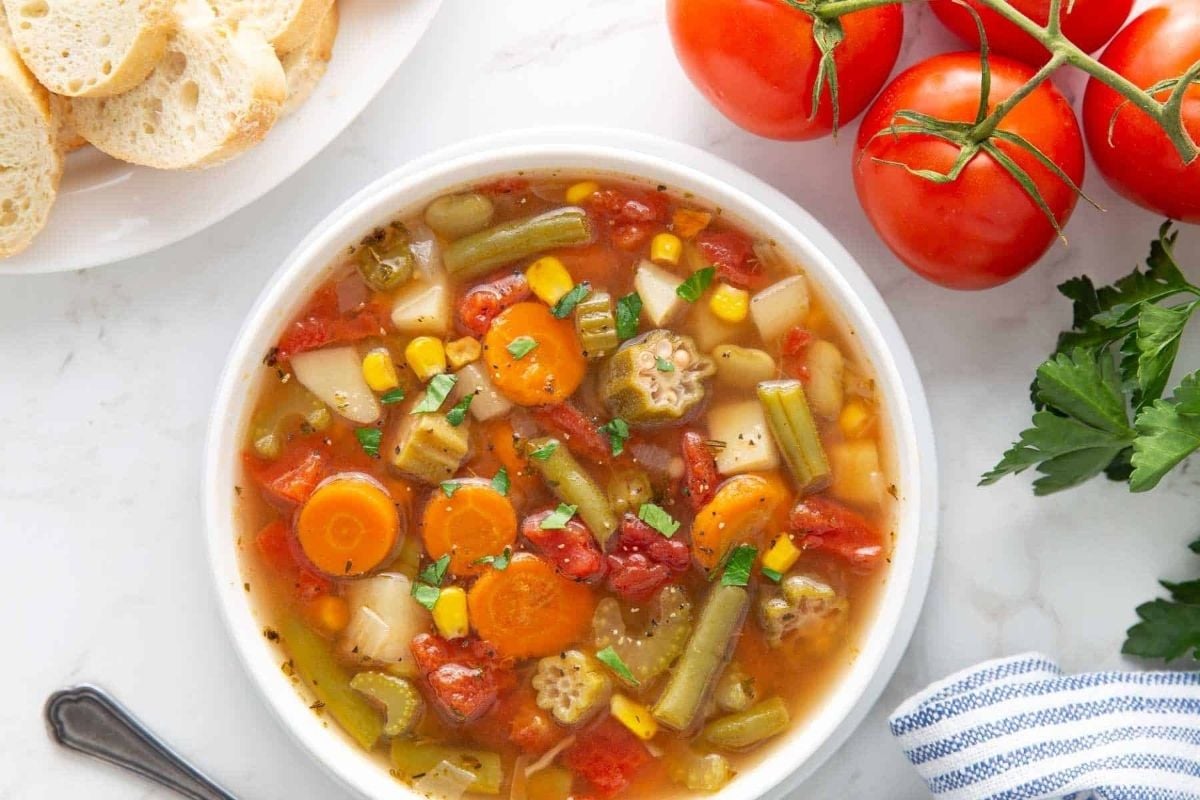 A wholesome bowl of vegetable soup with slowly cooked bread and juicy tomatoes.