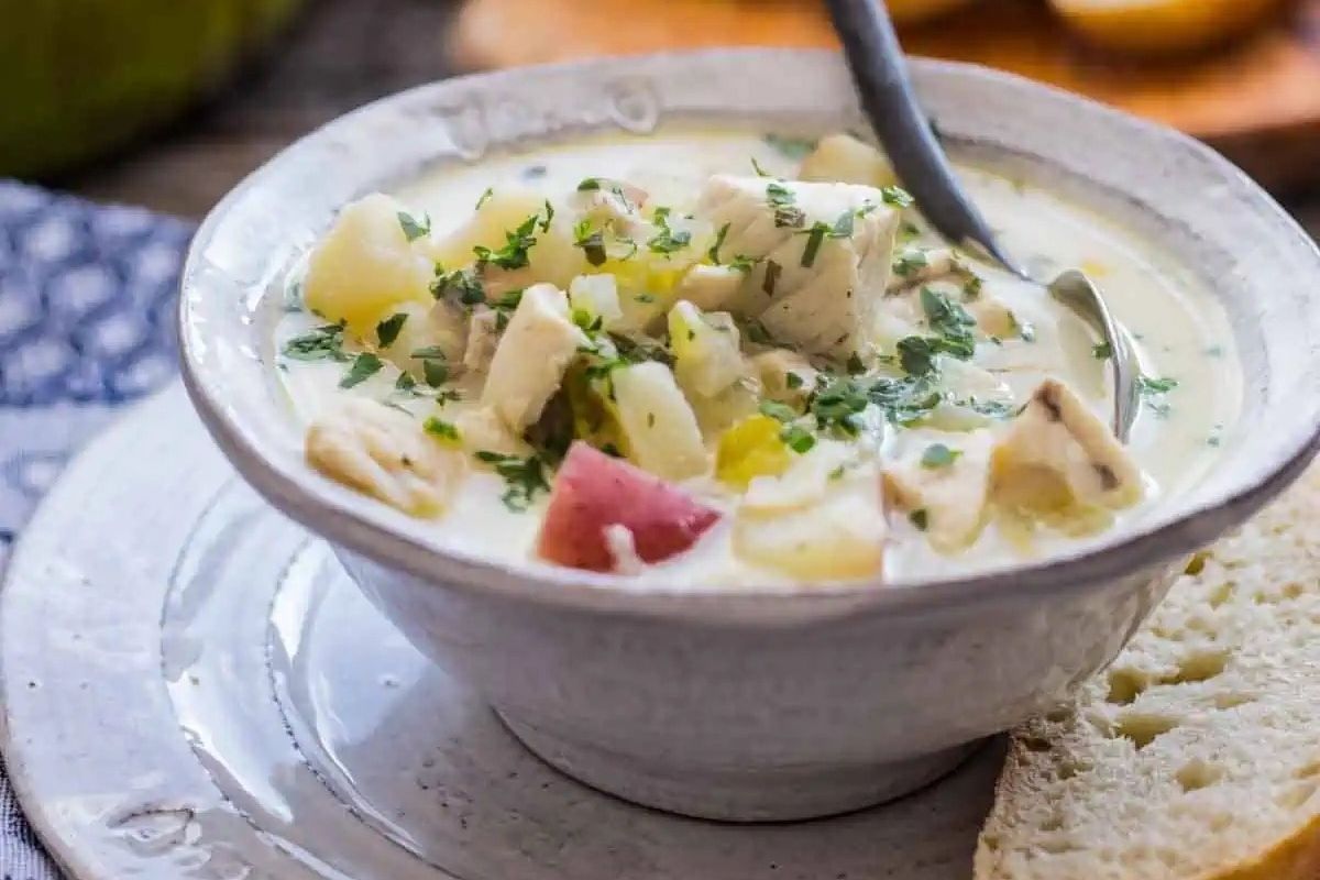 Chicken chowder recipe served in a white bowl with bread.