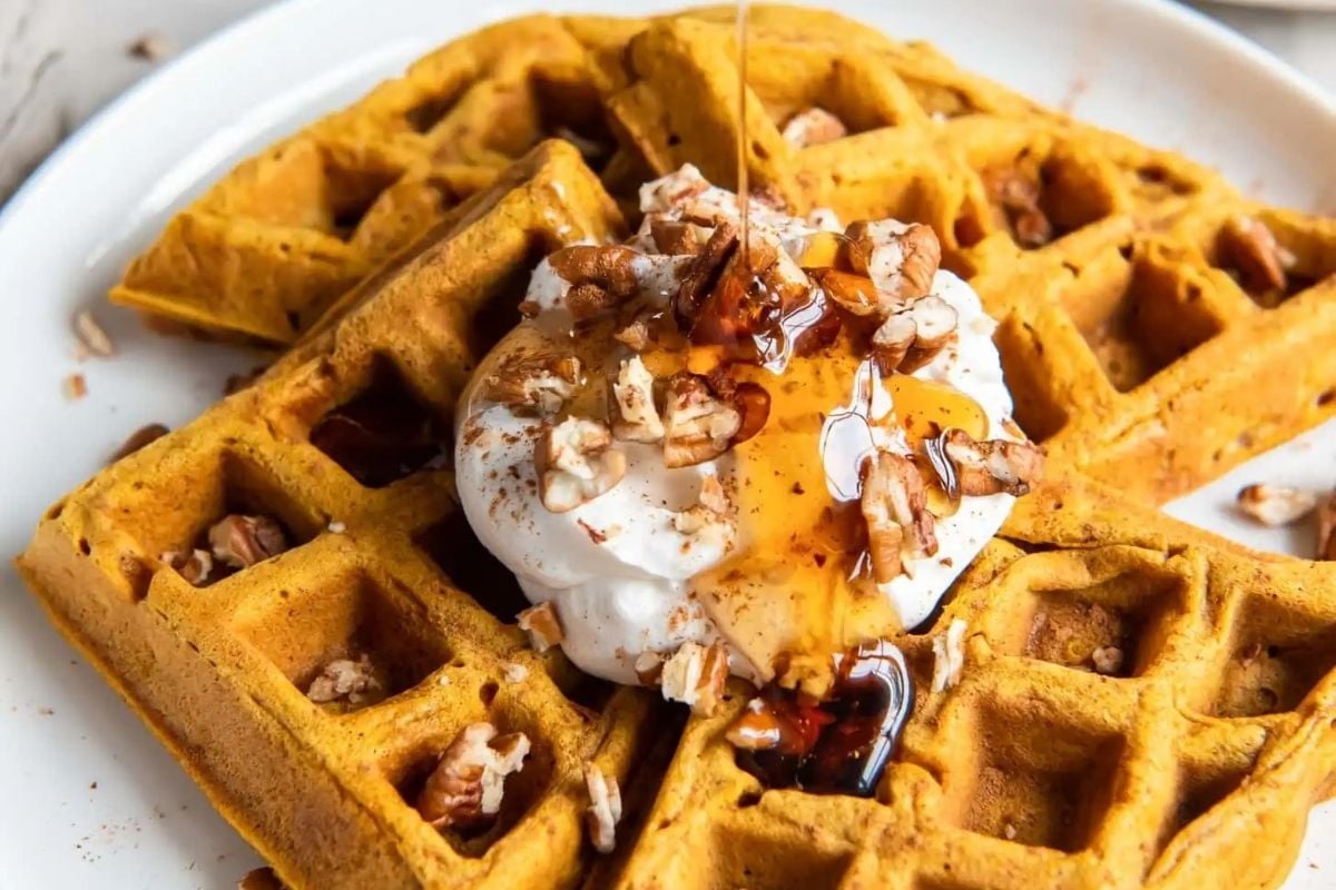 Divine pumpkin spice waffles served with fluffy whipped cream and topped with crunchy pecans.