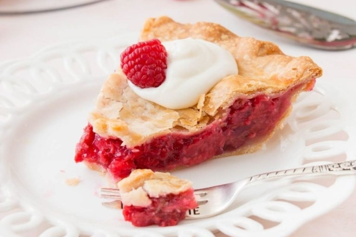 A slice of raspberry pie, perfect for Valentine's desserts, placed delicately on a white plate.